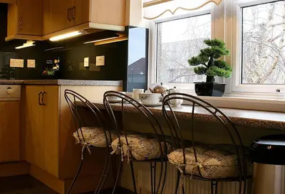 a kitchen with a counter with chairs and a window at Linden Apartment in Stirling