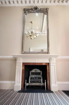 a living room with a fireplace with a mirror at Palmerston Suites in Edinburgh