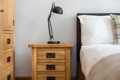 a lamp on a night stand next to a bed at Castle Vista, Grassmarket Apartment in Edinburgh