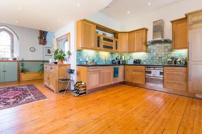 a large kitchen with wooden cabinets and a wooden floor at Eastkirk in Corrie