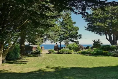 a garden with trees and the ocean in the background at Eastkirk in Corrie