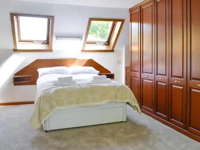 a bedroom with a bed with wooden furniture and windows at The Old Schoolhouse in Colfin