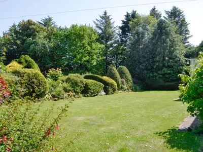 a garden with nicely trimmed bushes and trees at The Old Schoolhouse in Colfin