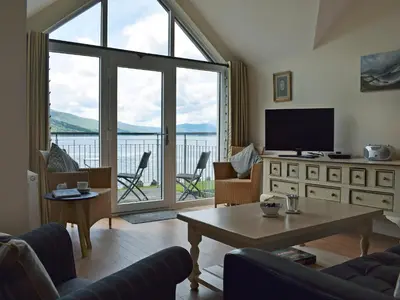 a living room with a television and a large window at The Bothy in Stron-fearnan