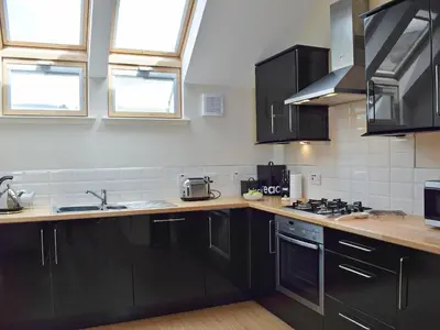 a kitchen with black cabinets and counters and windows at The Bothy in Stron-fearnan