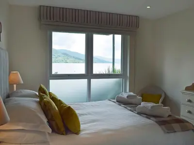 a bedroom with a large bed with a large window at The Bothy in Stron-fearnan