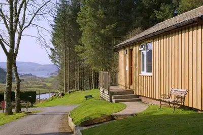 a small building with a bench next to a road at Lagnakeil Highland Lodges in Oban