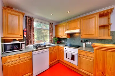 a kitchen with wooden cabinets and a red floor at Lagnakeil Highland Lodges in Oban