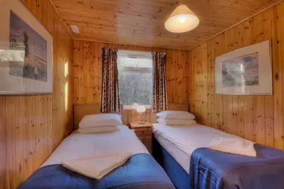 two twin beds in a room with wooden walls at Lagnakeil Highland Lodges in Oban