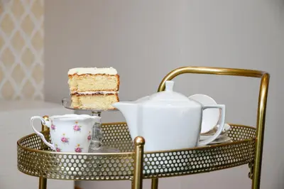 a gold serving cart with a cake and a tea set at Rowan Tree Apartment - Modern Apartment, Free Parking & Views in Oban