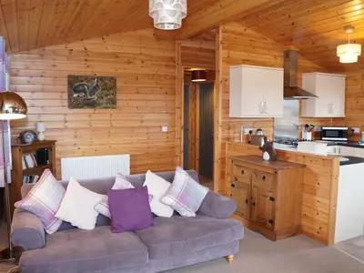 a living room with a couch and a kitchen at Chalet Osprey Lodge by Interhome in Kinross