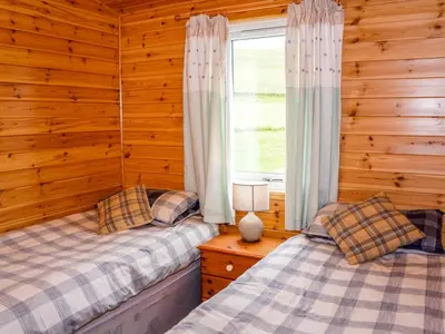 two beds in a log cabin with a window at Chalet Osprey Lodge by Interhome in Kinross