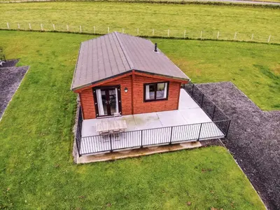 a small house with a deck in a field at Chalet Osprey Lodge by Interhome in Kinross
