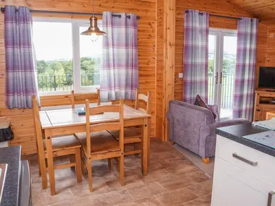 a dining room with a table and a couch at Chalet Osprey Lodge by Interhome in Kinross