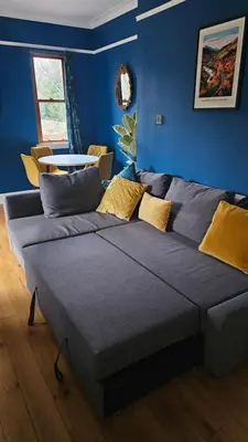 a large couch in a room with a blue wall at Beautiful self contained apartment with garden in Glasgow