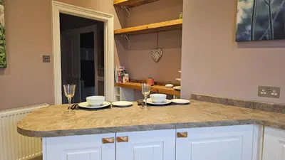 a kitchen with a counter with glasses and plates on it at Beautiful self contained apartment with garden in Glasgow