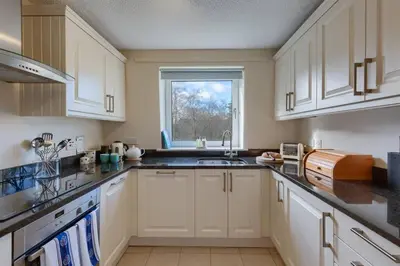 a kitchen with white cabinets and a window at 45 Guthrie Court, Fantastic top floor apartment next to Gleneagles in Auchterarder