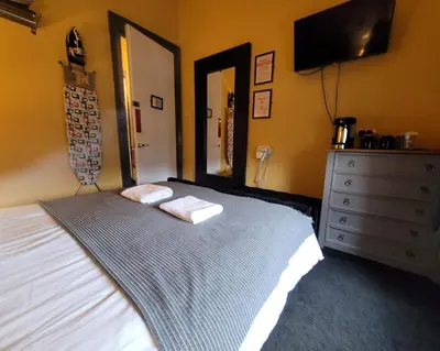 a bedroom with a bed and a dresser and a television at Stay - Gilmore Guesthouse in Edinburgh