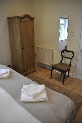 a bedroom with a bed and a chair and a window at Arrochoile Cottage in Glasgow