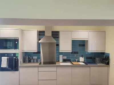 a kitchen with white cabinets and a stove at Arrochoile Cottage in Glasgow