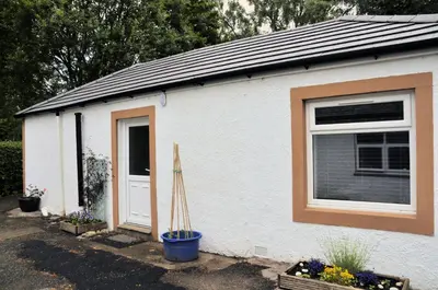 a white building with a window and a door at Arrochoile Cottage in Glasgow
