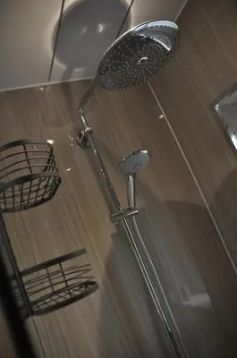 a shower with a shower head on top of a wooden floor at Arrochoile Cottage in Glasgow