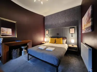 a bedroom with a bed with yellow pillows and a fireplace at Frederick Douglass - Rooms In The City in Edinburgh