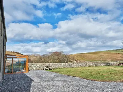 a building with a stone wall and a picnic table at Midcraigs in Kilchenzie