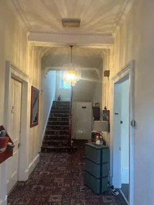 a hallway with a chandelier and stairs in a house at Dellwood Hotel in Campbeltown