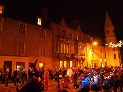 a large crowd of people walking down a street at night at Argyll Arms Hotel in Campbeltown