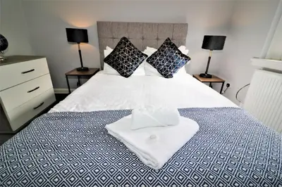 a bedroom with a blue and white bed with two lamps at Signature - Carfin House in Carfin