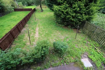 a yard with a fence and some bushes at Signature - Carfin House in Carfin