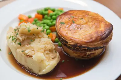a plate of food with a pie and vegetables at Babbity Bowsters in Glasgow
