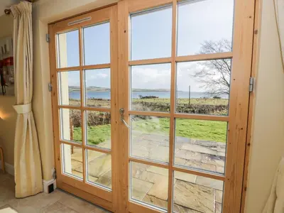 a door with a view of the ocean seen through it at Ettrick Cottage in Port Bannatyne