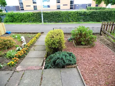 a garden with flowers and a walkway at Black Cart House in Johnstone