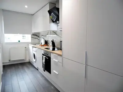 a kitchen with white cabinets and a washer and dryer at Black Cart House in Johnstone