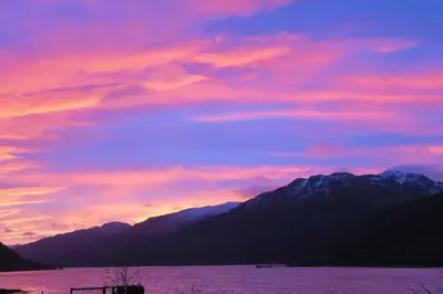 a sunset over a body of water with mountains at TwoStones Self Catering Cottage in Arrochar