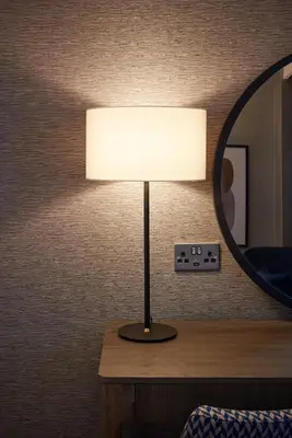 a lamp on a table next to a mirror at voco Edinburgh - Haymarket by IHG in Edinburgh