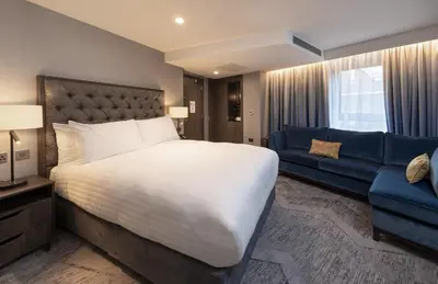 a bedroom with a large bed and a blue couch at voco Edinburgh - Haymarket by IHG in Edinburgh