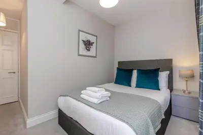 a small bedroom with a bed with blue pillows at Dragon Suites - Edinburgh City Centre 2 Bed Apartment in Edinburgh