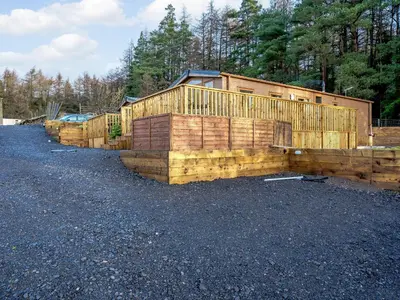 a row of wooden buildings on a gravel road at The Paddocks - Uk7112 in Alloa