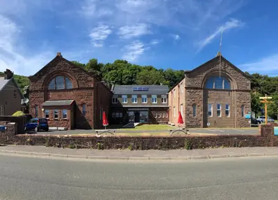 a building with two red umbrellas in front of it at FSC Millport Hostel in Millport
