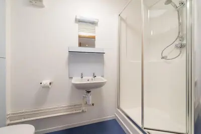a white bathroom with a sink and a shower at FSC Millport Hostel in Millport