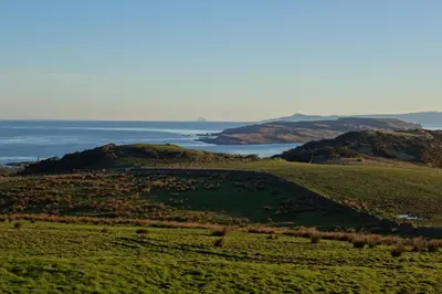 a green field with the ocean in the background at FSC Millport Hostel in Millport