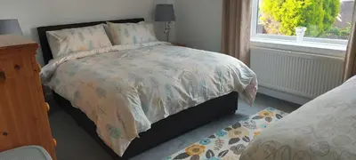 a bedroom with a bed with a comforter and a window at LAWFIELD R&R in West Kilbride