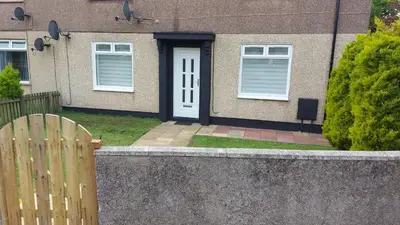 a house with a white door and a fence at LAWFIELD R&R in West Kilbride