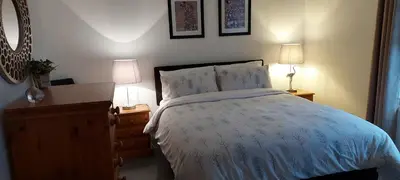 a bedroom with a bed and two lamps and a dresser at LAWFIELD R&R in West Kilbride