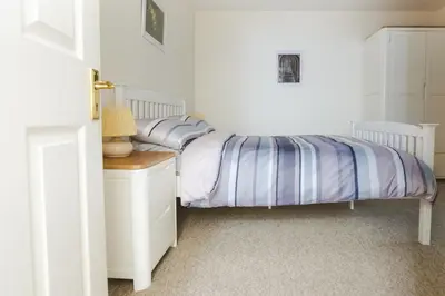 a bedroom with two beds and a table with a lamp at Clyde View B&B in Dunoon