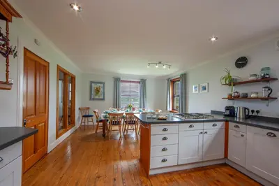 a kitchen with white cabinets and a table with chairs at Seabank Lochside Farmhouse in Oban