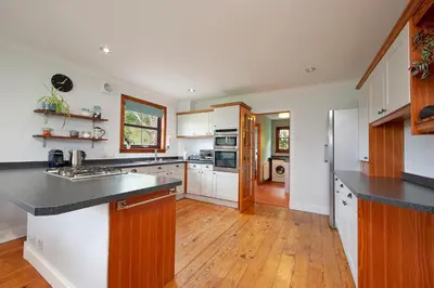 a kitchen with white cabinets and a wooden floor at Seabank Lochside Farmhouse in Oban